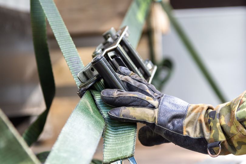 Person with hand on belt securing shipment