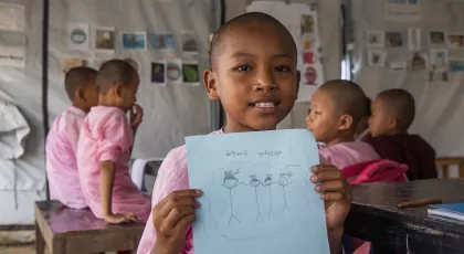 Child holding a drawing in a UNICEF-supported learning space, representing Fracht Group North America's partnership with UNICEF USA to support children affected by humanitarian crises.