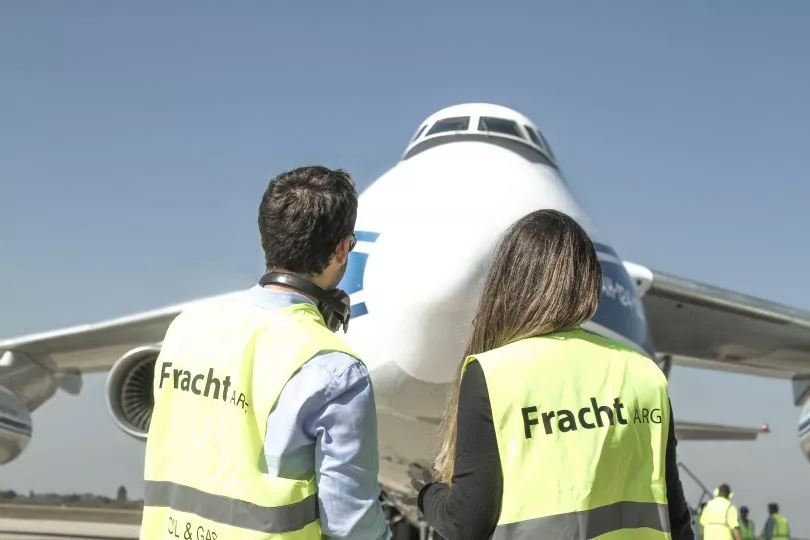 Two Fracht employees on a runway looking at a plane