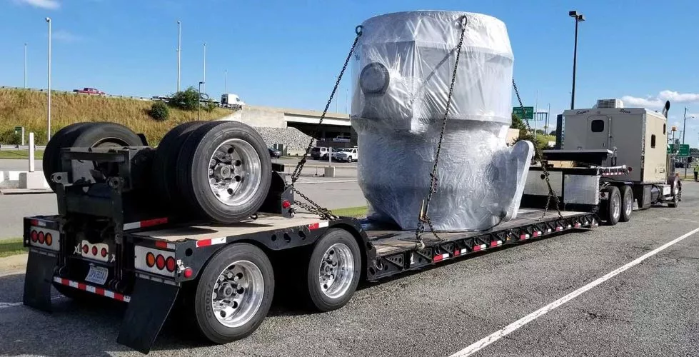 Truck carrying large piece of cargo strapped in