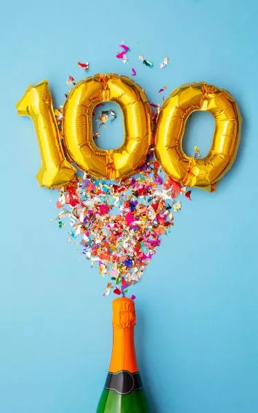 Balloons showing 100 with confetti and bottle of champagne