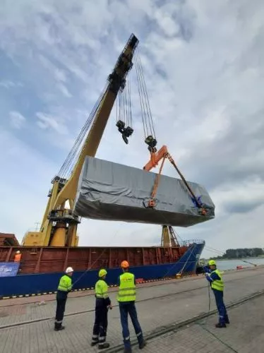 Group of employees inspect cargo on crane